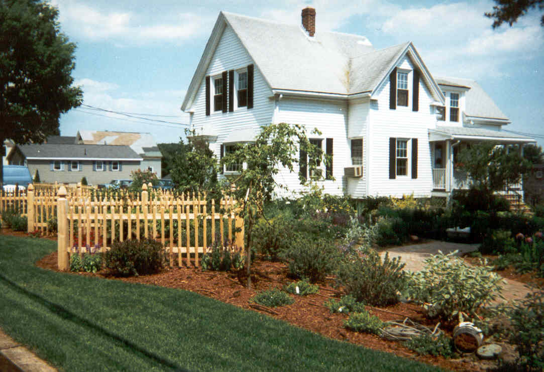 The white Estabrook family farmhouse with a garden and picket fence